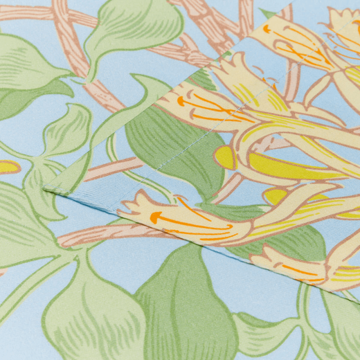 A detail of the pocket of a cotton apron with a light blue, green and yellow honeysuckle pattern.