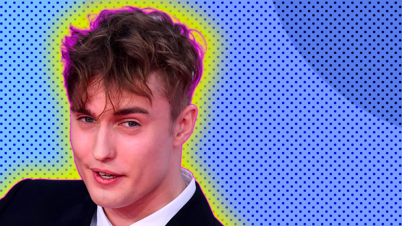 Sam Fender looking out to an audience half smiling against a blue dotted background with a yellow halo.